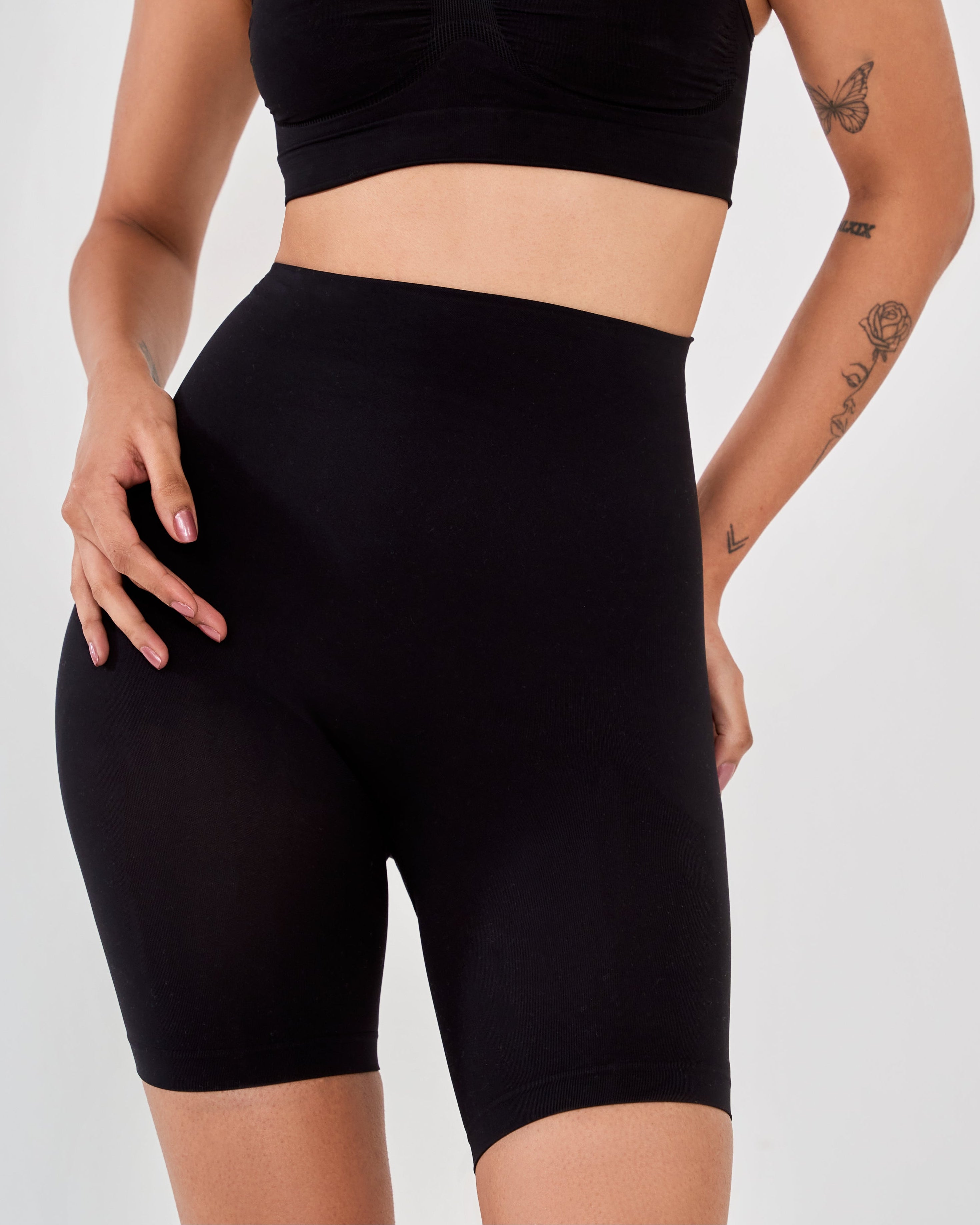 Close-up front view of woman wearing black high-waisted shaper shorts showing seamless tummy and thigh-sculpting fit.
